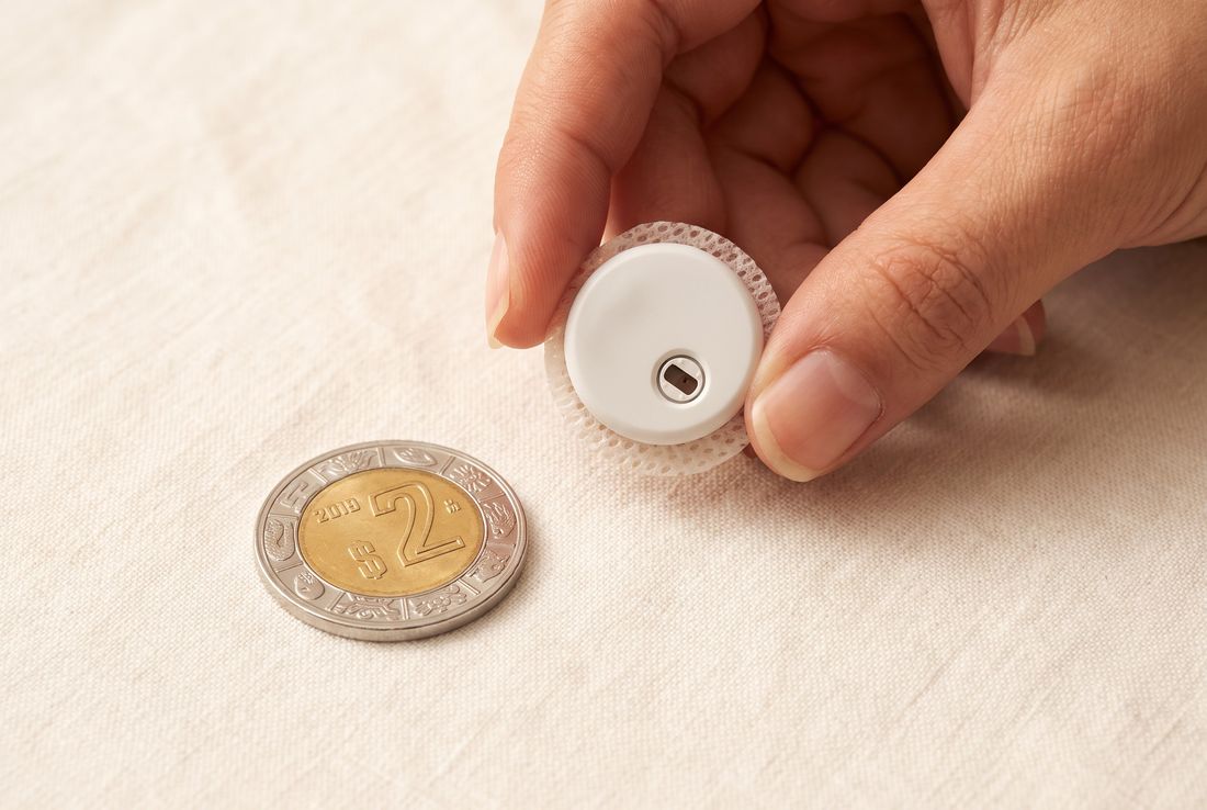 Sensor QiTrax junto a una moneda de 2 pesos para comparar su tamaño