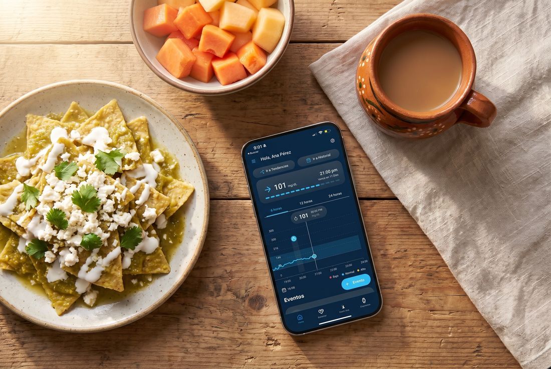 Desayuno de chilaquiles y fruta con el celular mostrando la app QiTrax